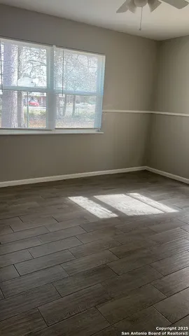 an empty room with wooden floor and windows