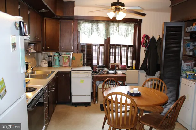a kitchen with stainless steel appliances kitchen island granite countertop a table chairs in it and a window