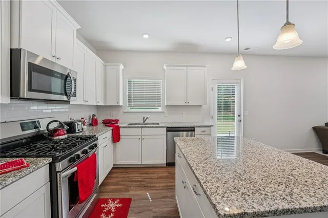 a kitchen with kitchen island a sink stainless steel appliances and cabinets