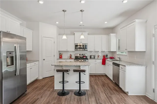 a kitchen with a refrigerator a sink dishwasher a stove and white cabinets with wooden floor