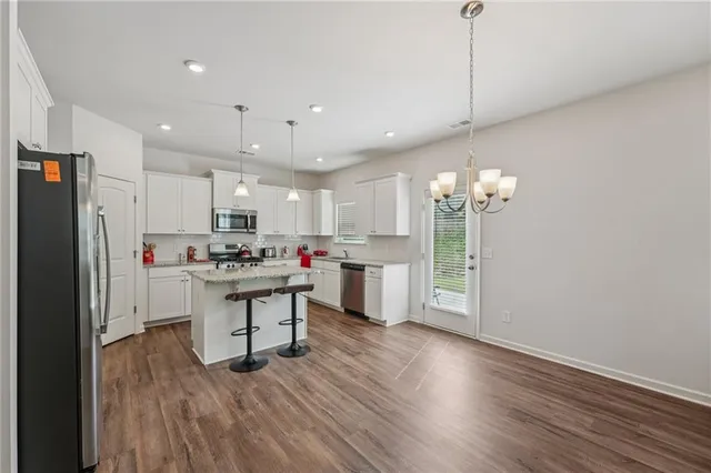 a kitchen with stainless steel appliances a refrigerator sink cabinets wooden floor and a window