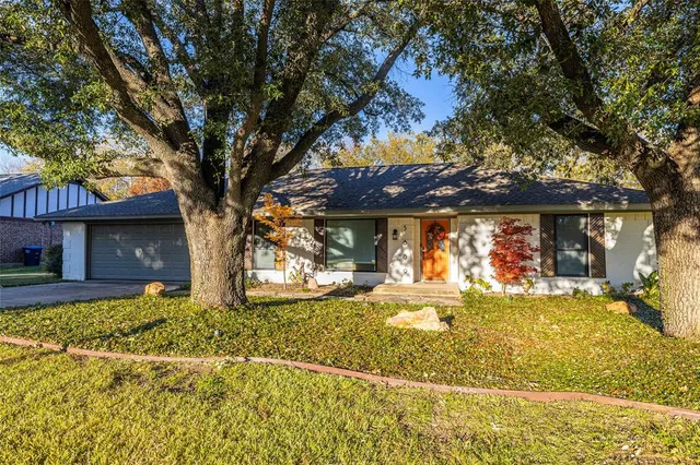a view of a house with a large tree and a yard