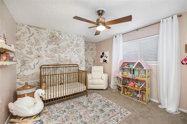 a bedroom with a baby bed a couch and a chandelier