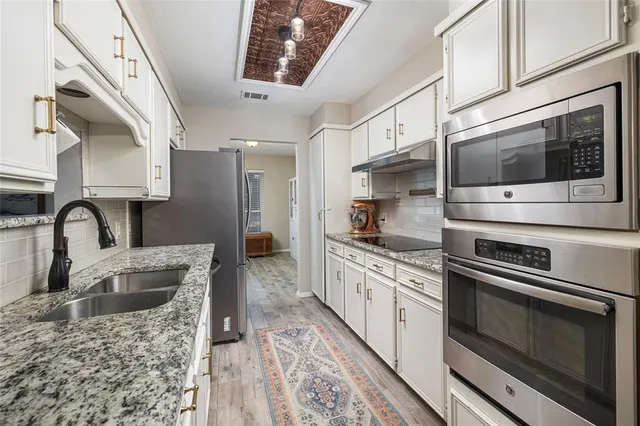 a kitchen with stainless steel appliances granite countertop a stove a sink and a microwave