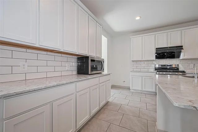 a kitchen with stainless steel appliances granite countertop a sink a stove and white cabinets