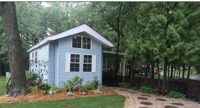 a view of a yard in front of a house with plants and large trees
