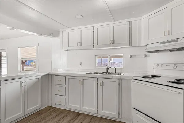 a kitchen with stainless steel appliances granite countertop a sink and cabinets with wooden floor