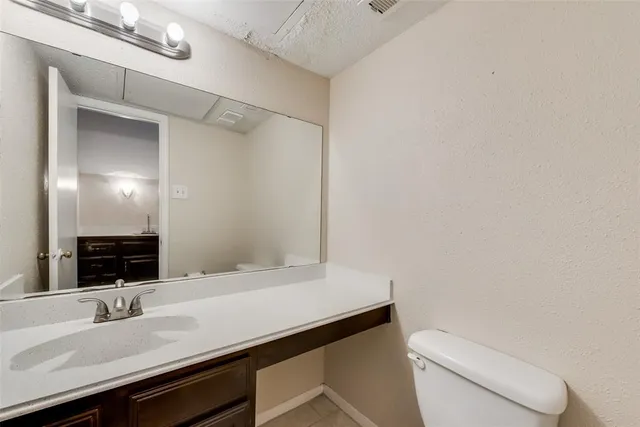 a bathroom with a granite countertop sink a toilet and a mirror