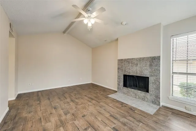 an empty room with windows fireplace and fan