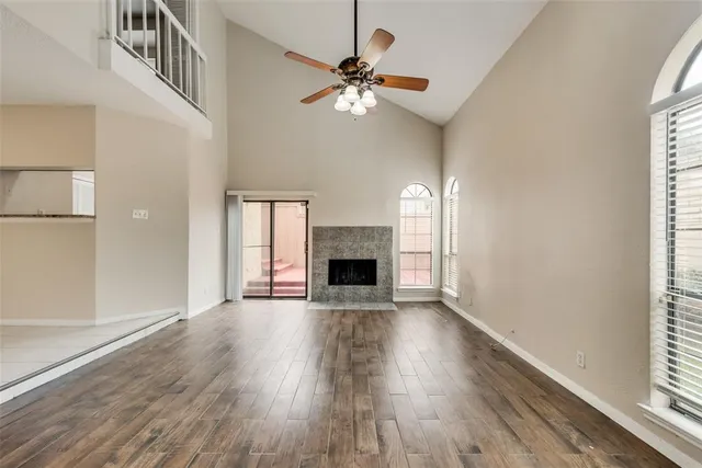 a view of a livingroom with a fireplace a ceiling fan and windows