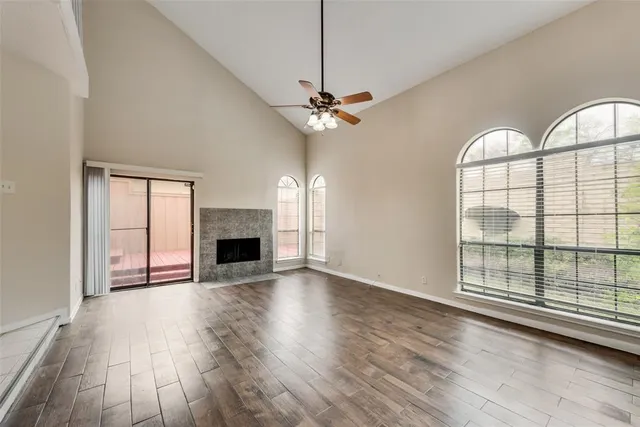 an empty room with wooden floor fireplace and windows