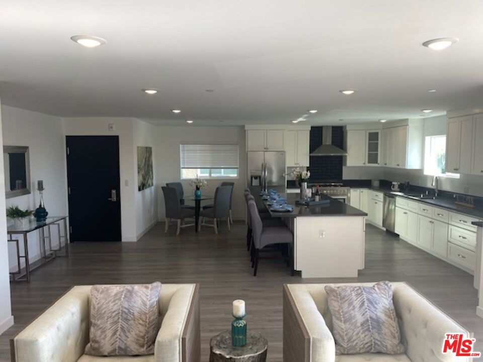 a living room with couches and kitchen view with wooden floor