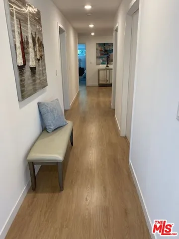 a living room with stainless steel appliances furniture a rug and a kitchen view