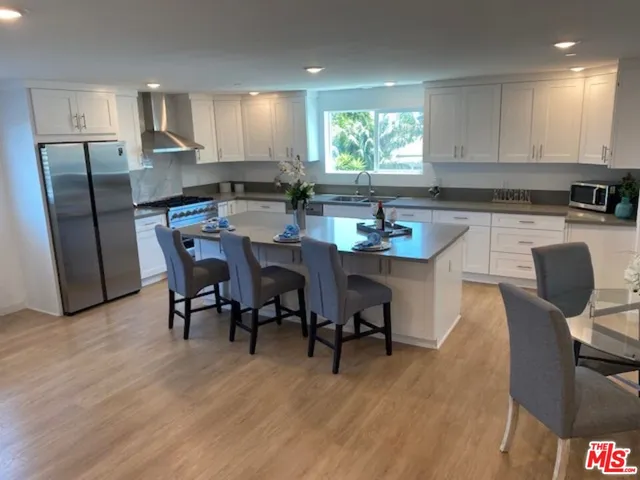 a kitchen with stainless steel appliances granite countertop a table chairs sink refrigerator and cabinets