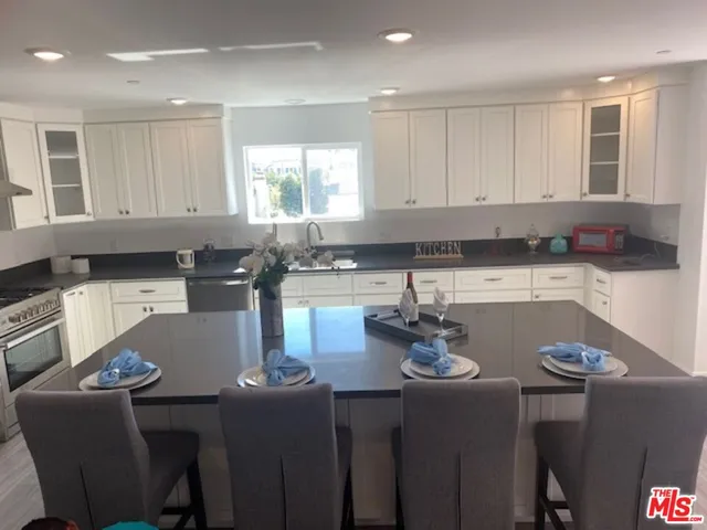 a kitchen with stainless steel appliances granite countertop a stove a sink a microwave a dining table and chairs