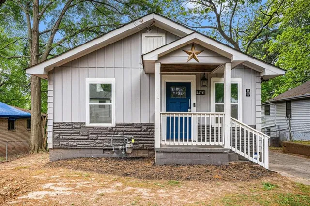 a view of a house with a small yard and a large tree