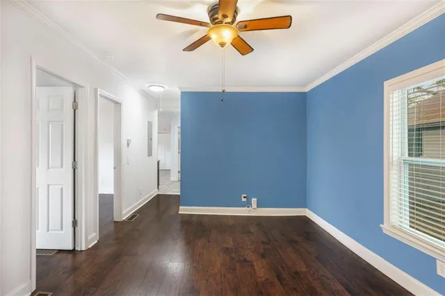 an empty room with wooden floor closet and windows