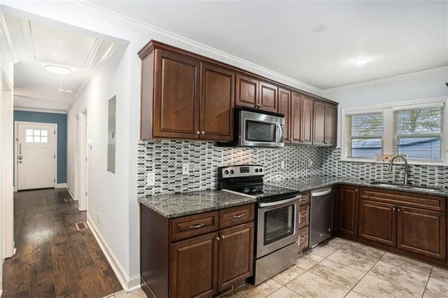 a kitchen with stainless steel appliances granite countertop wooden cabinets stove top oven and sink