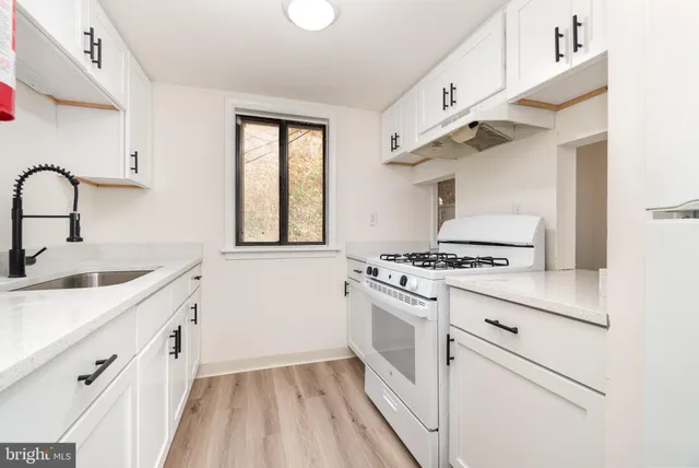a kitchen with white cabinets stove and sink