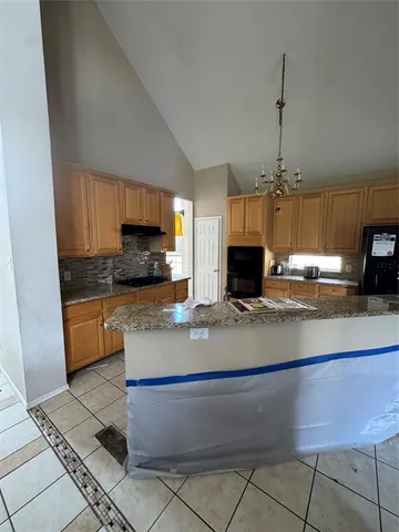 a kitchen with kitchen island granite countertop a sink a counter top space cabinets and stainless steel appliances