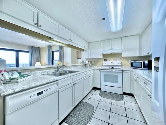 a kitchen with granite countertop stainless steel appliances a sink window and cabinets