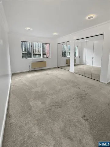 a view of an empty room with a window and cabinet
