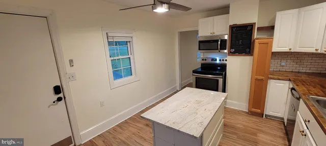 a kitchen with stainless steel appliances kitchen island granite countertop a refrigerator stove top oven and sink