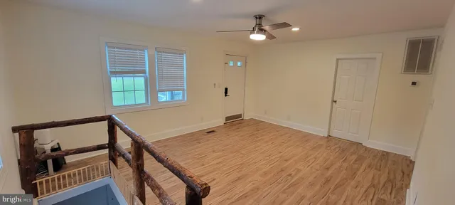 a view of empty room with wooden floor and fan
