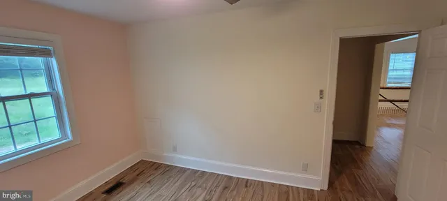 a view of hallway with window and wooden floor