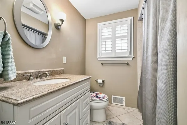 a bathroom with a granite countertop toilet sink and mirror