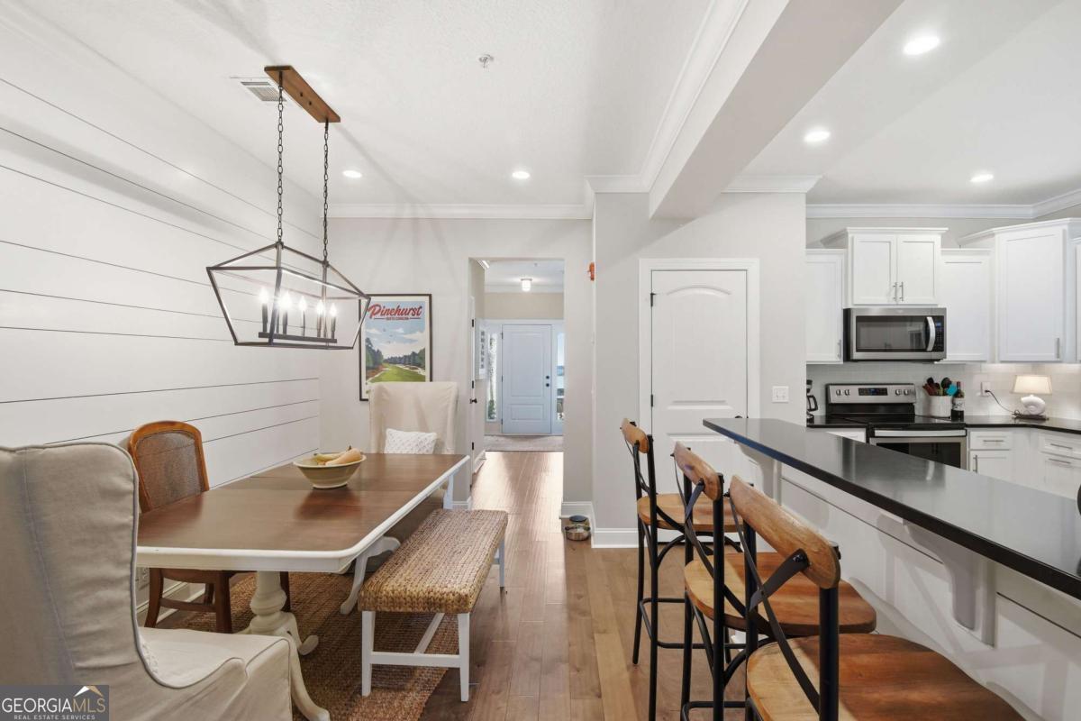 203 Mariners Circle St. Simons, GA 31522 - Photo 7 of 32 a kitchen with stainless steel appliances kitchen island granite countertop a dining table chairs a sink and dishwasher a refrigerator with wooden floor