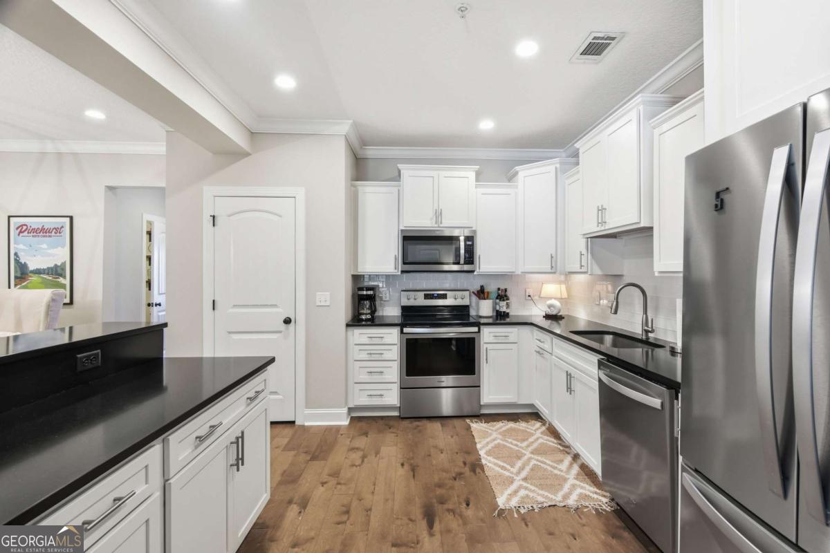 203 Mariners Circle St. Simons, GA 31522 - Photo 10 of 32 a large kitchen with stainless steel appliances granite countertop a refrigerator a stove and a sink