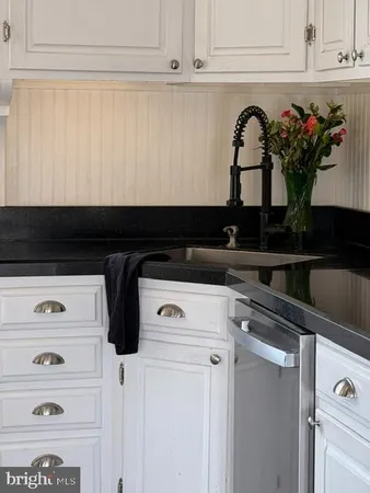 a kitchen with white cabinets and sink