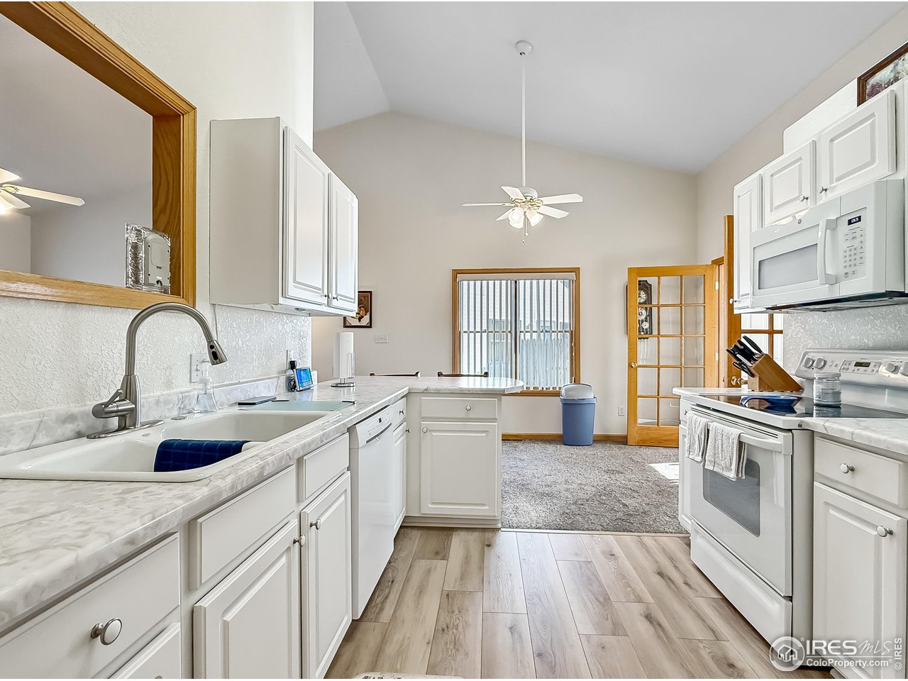 817 Mindy Circle, Unit B Sterling, CO 80751 - Photo 11 of 34 a kitchen with a sink dishwasher a stove and white cabinets with wooden floor