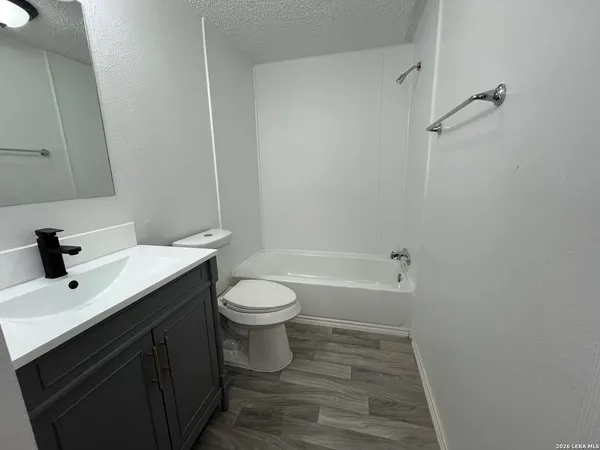 a bathroom with a bathtub shower sink vanity and toilet