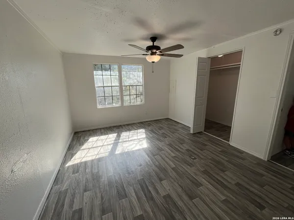a view of empty room with wooden floor and fan