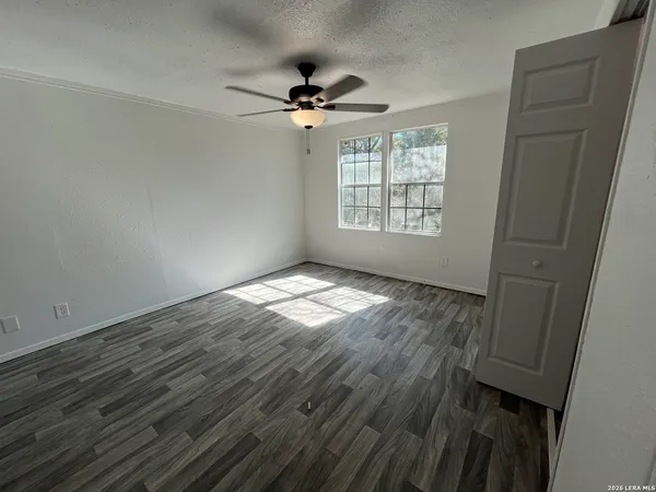 a view of empty room with wooden floor and fan