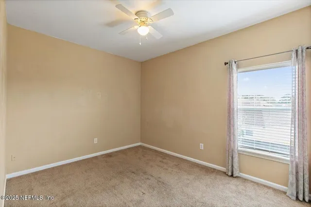 an empty room with a ceiling fan and a window