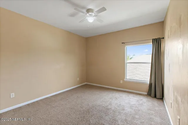 an empty room with a window and a fan