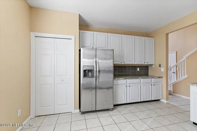 a kitchen with white cabinets a refrigerator and white cabinets