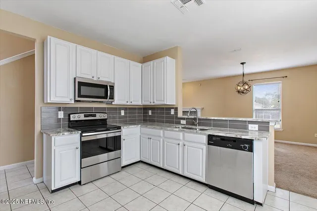 a kitchen with white cabinets appliances and sink