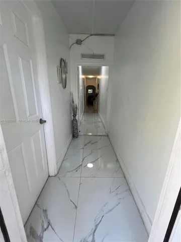 a view of a hallway to a house with white walls