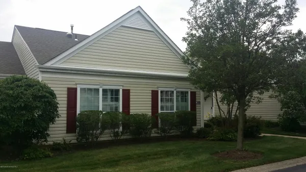 a view of a white house next to a yard with big trees