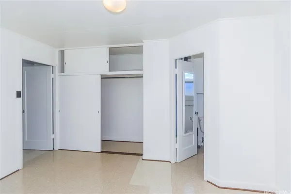 a view of an empty room with closet and a window