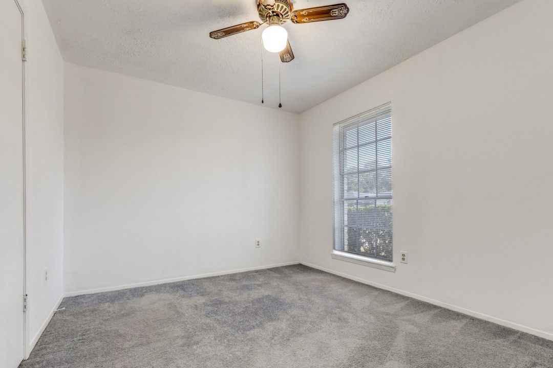 16210 Tibet Road Friendswood, TX 77546 - Photo 16 of 27 en empty room with windows and ceiling fan
