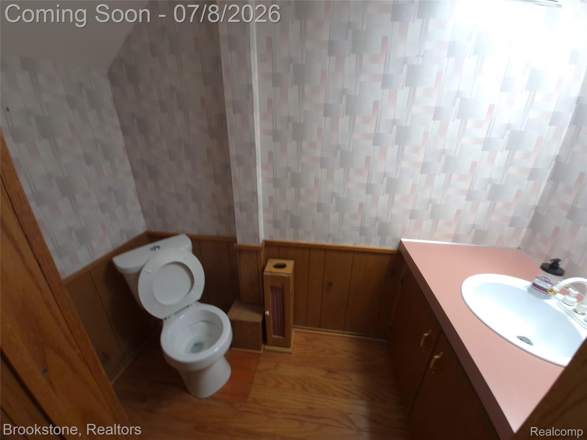 4140 South Henderson Road Davison, MI 48423 - Photo 73 of 98 Bathroom featuring wood-finish flooring, wood paneling, a white toilet, and a vanity with a drop-in sink