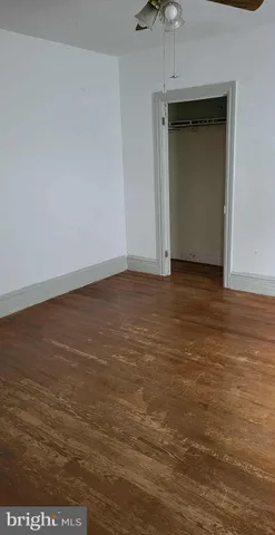 a view of an empty room with closet and a ceiling fan