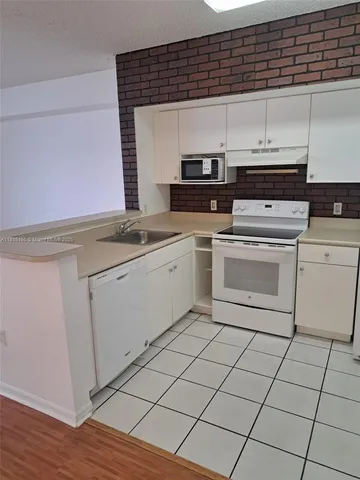 a kitchen with a stove cabinets and wooden floor