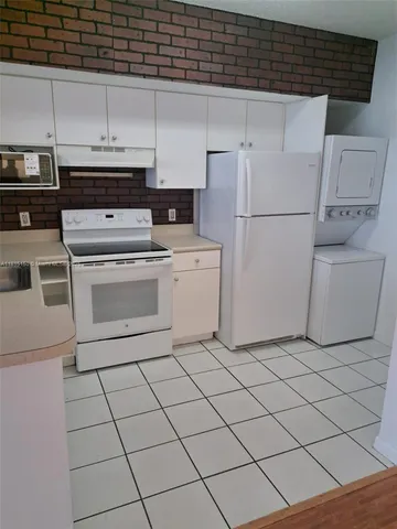 a white kitchen with cabinets a sink and white appliances