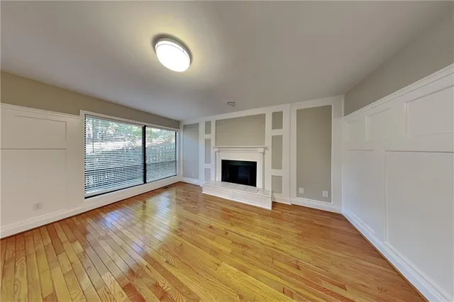 a view of empty room with wooden floor and fireplace